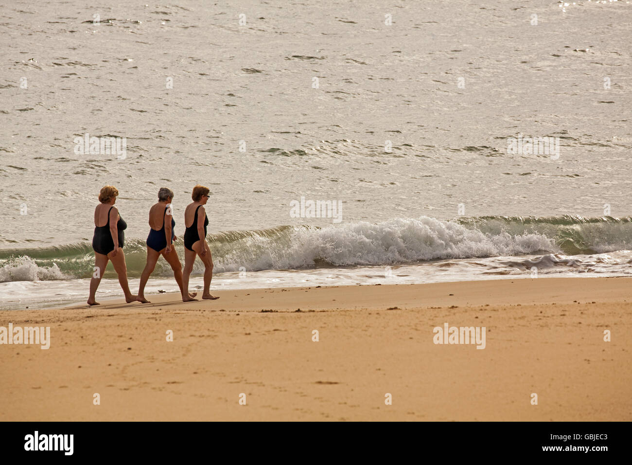 Trois grosses femmes portant des maillots de marcher le long de la plage sur le bord de la mer du Nord de l'Espagne à Comillas Banque D'Images