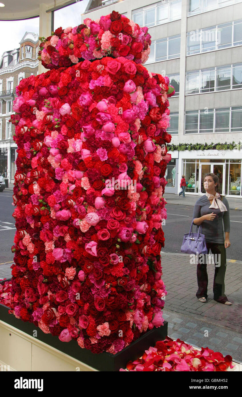 Une passeuse admire une grande bouteille de parfum faite de roses dans la fenêtre de JO Malone, sur Sloane Street tandis que le quartier commercial Sloane à Londres est transformé en un grand concours de mode floral pour Sloane à Bloom, Jugé par la Royal Horticultural Society, il est coordonné chaque année à l'appui du RHS Chelsea Flower Show. Banque D'Images