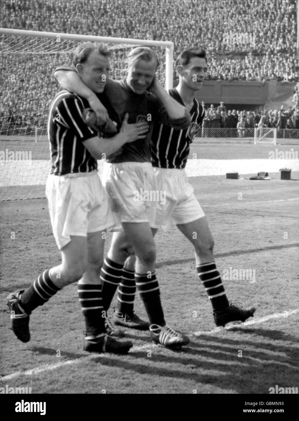 Dave Ewing (l) et Bill Levers (r) de Manchester City aident le gardien de but Bert Trautmann (c) à sortir du terrain après leur victoire de 3-1. Trautmann avait cassé son cou en faisant une économie aux pieds de Peter Murphy de Birmingham City Banque D'Images