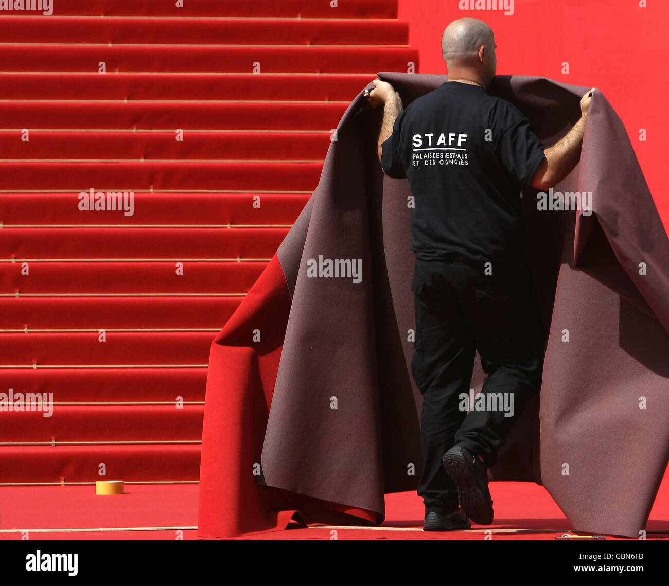 Les ouvriers préparent le tapis rouge sur les marches du Palais des Festivals, à Cannes, en France, avant le début du Festival de Cannes. Banque D'Images