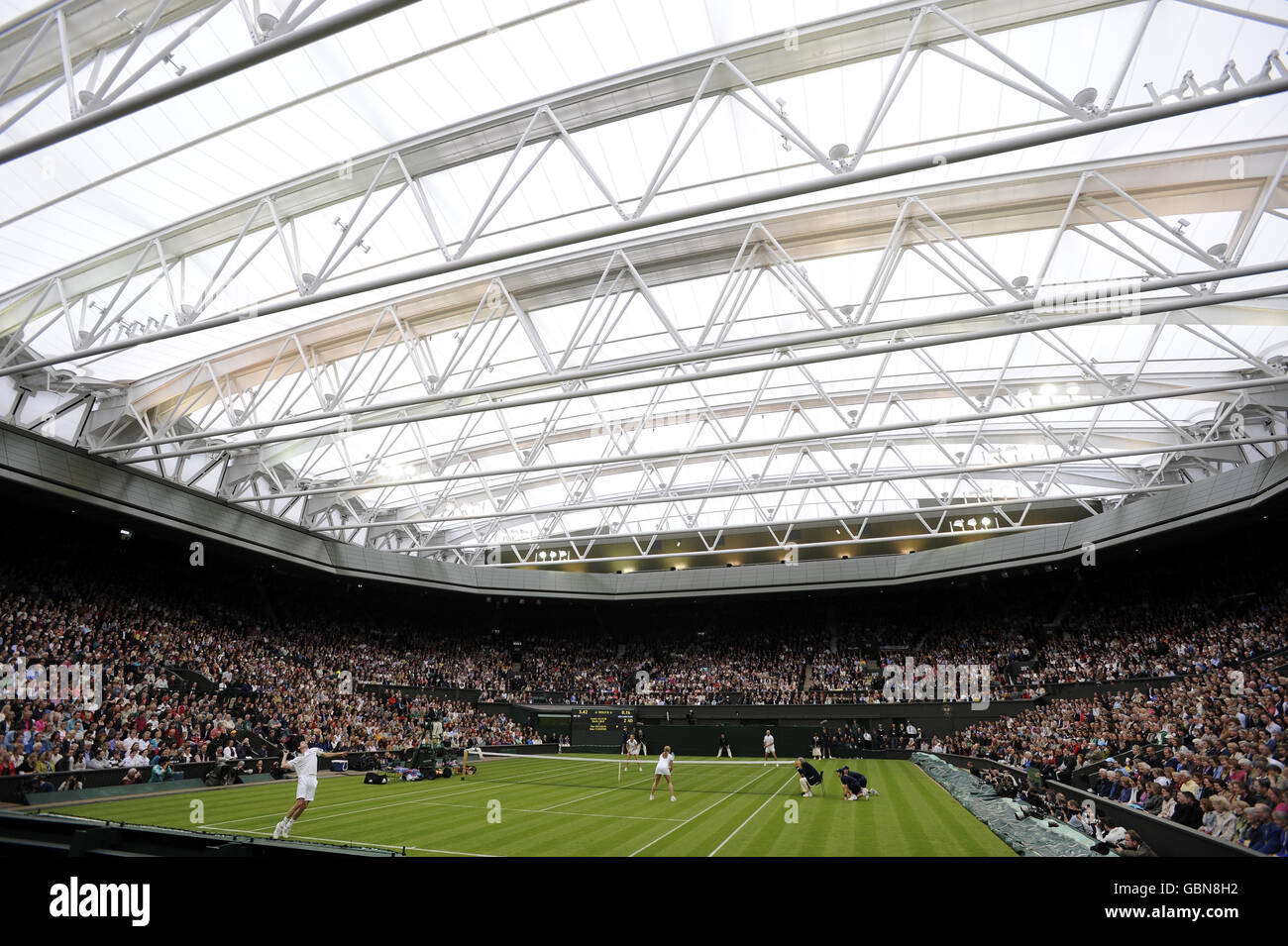 Tim Henman (à gauche), en Grande-Bretagne, servant sur le court central avec son partenaire Kim Clijsters contre Andre Agassi et sa femme Steffi Graf, lors de la célébration du court du Centre au All England Lawn tennis and Croquet Club, Wimbledon, Londres. Banque D'Images