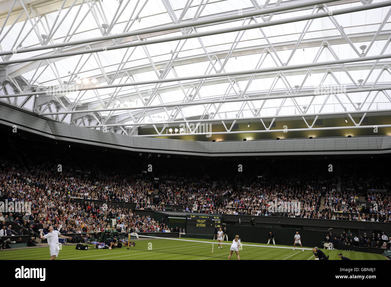 Tim Henman (à gauche), en Grande-Bretagne, servant sur le court central avec son partenaire Kim Clijsters contre Andre Agassi et sa femme Steffi Graf, lors de la célébration du court du Centre au All England Lawn tennis and Croquet Club, Wimbledon, Londres. Banque D'Images