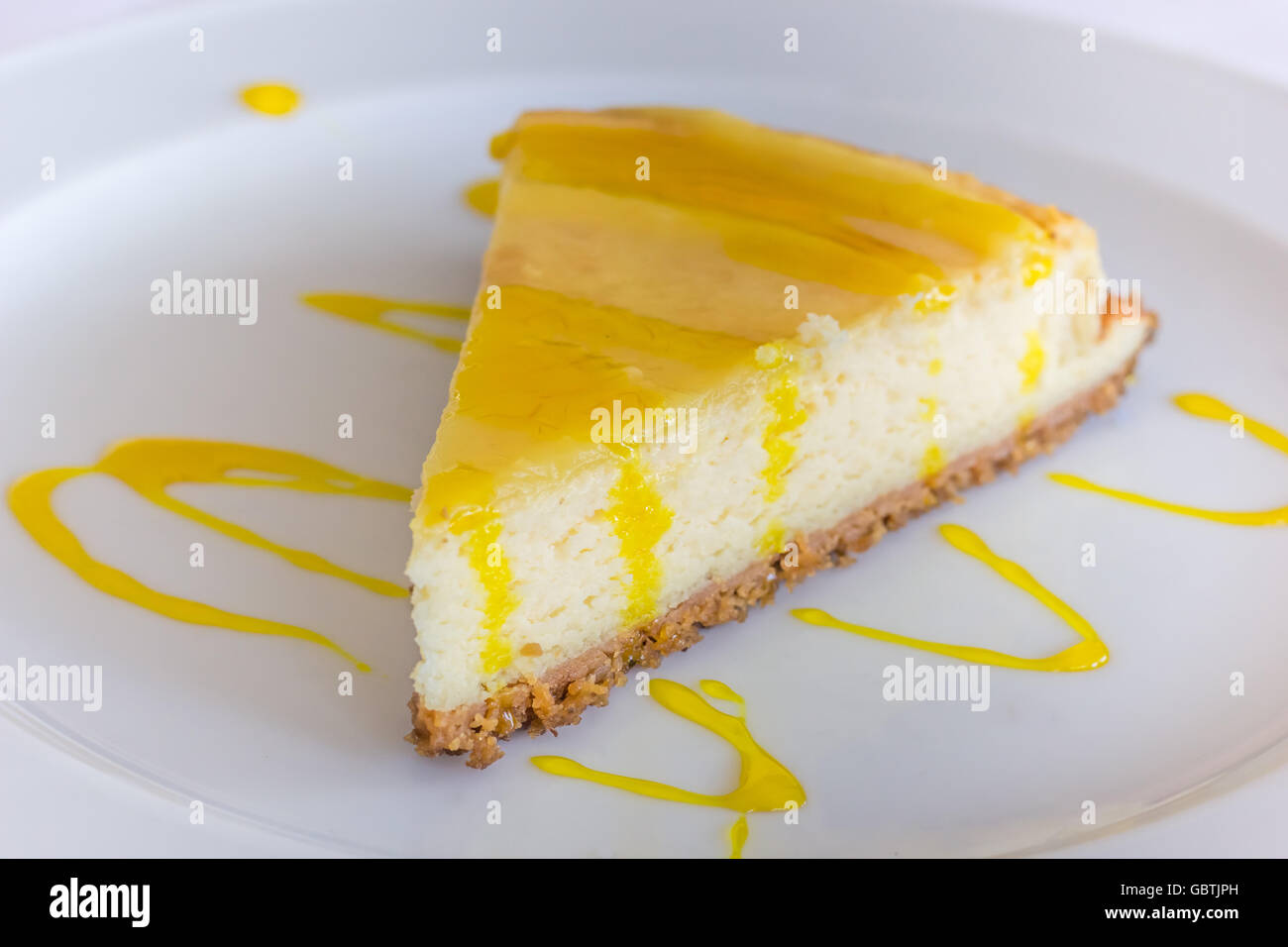 Gâteau au fromage au citron avec la sauce servi sur une plaque blanche Banque D'Images