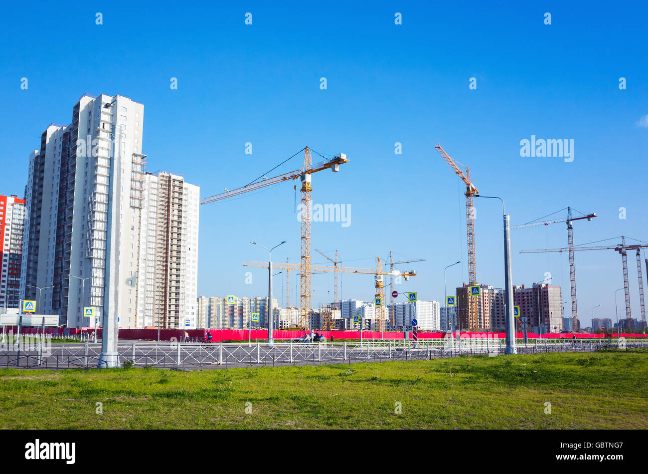 Bloc d'appartements en construction, des grues de travail sont sous ciel bleu dans la journée d'été Banque D'Images