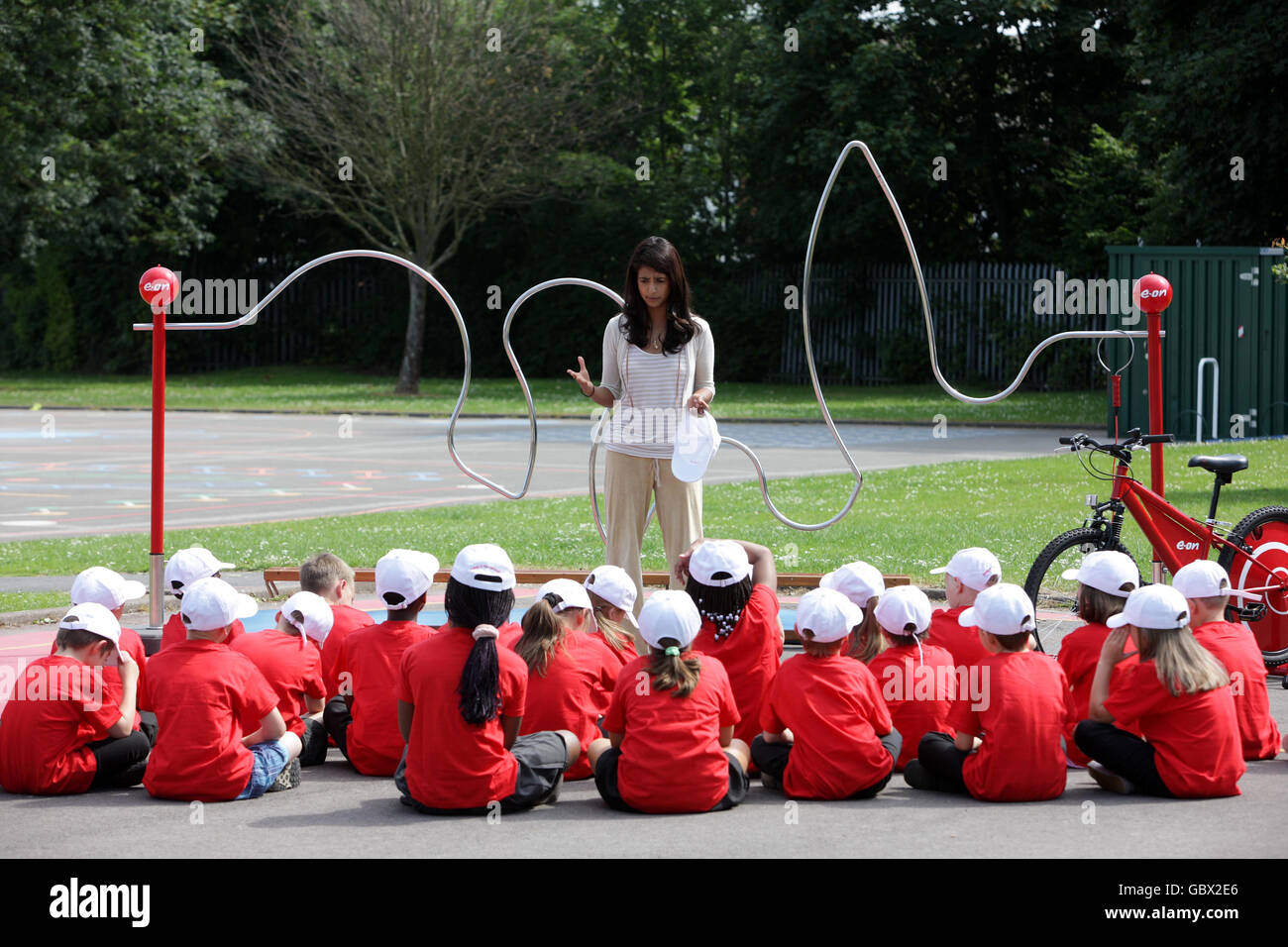 Konnie Huq, présentateur de télévision, se tient devant un jeu de bruiteur électrique à pédale géant lors d'un cours de sciences en plein air à l'école primaire de Limbrick Wood à Coventry. Banque D'Images