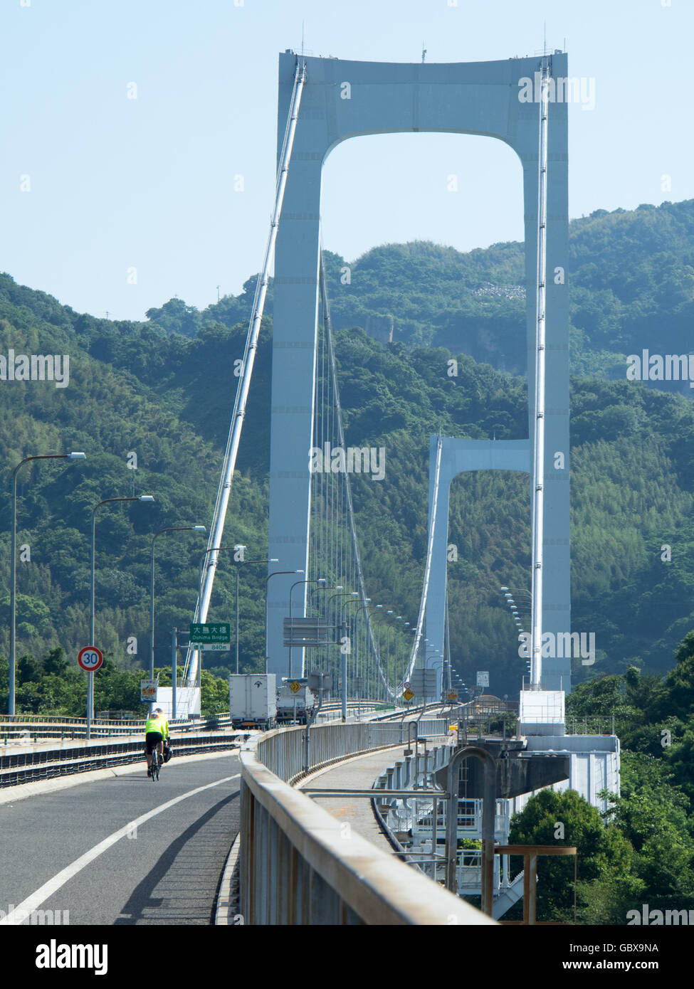 Deux cyclistes traversant le pont reliant l'Hakata Oshima Oshima et îles de Hakata dans la mer intérieure de Seto. Banque D'Images