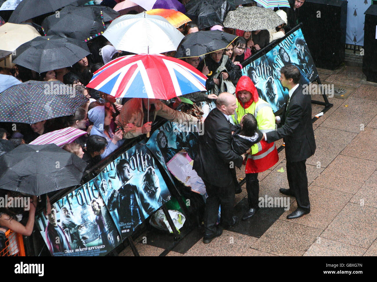 Un fan est enlevé de la foule pendant la forte pluie à la première mondiale de Harry Potter et le Prince de sang-mêlé à l'Odeon Leicester Square, Londres. Banque D'Images