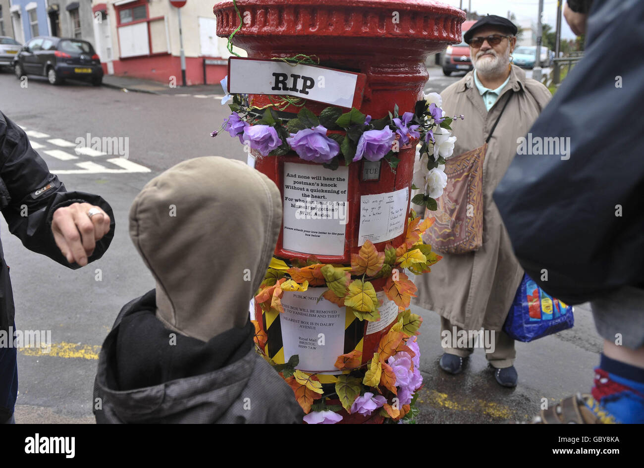 Les gens regardent une boîte postale à Bedminster, Bristol, qui a été retirée de l'usage public. La boîte postale a été transformée en une œuvre d'art, ornée de poésie, de fleurs et d'insignes religieux, après qu'elle ait été fermée par le Royal Mail. Banque D'Images