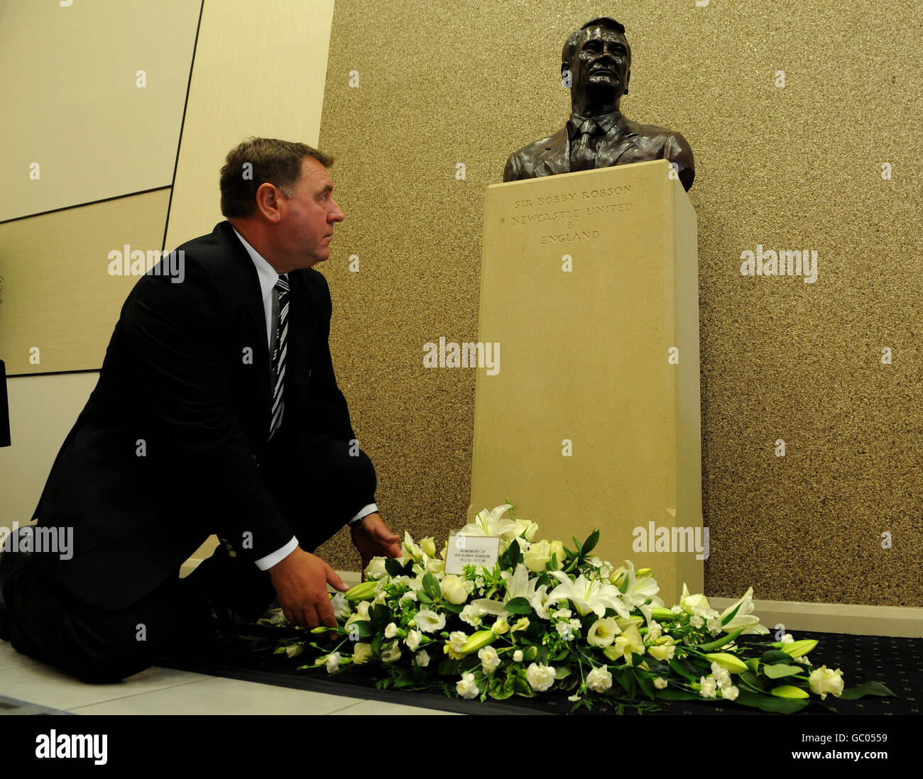 Un membre du personnel de Newcastle Utd dépose des fleurs à la statue de Sir Bobby Robson, à l'entrée des joueurs du parc St James' Park, à Newcastle. Banque D'Images