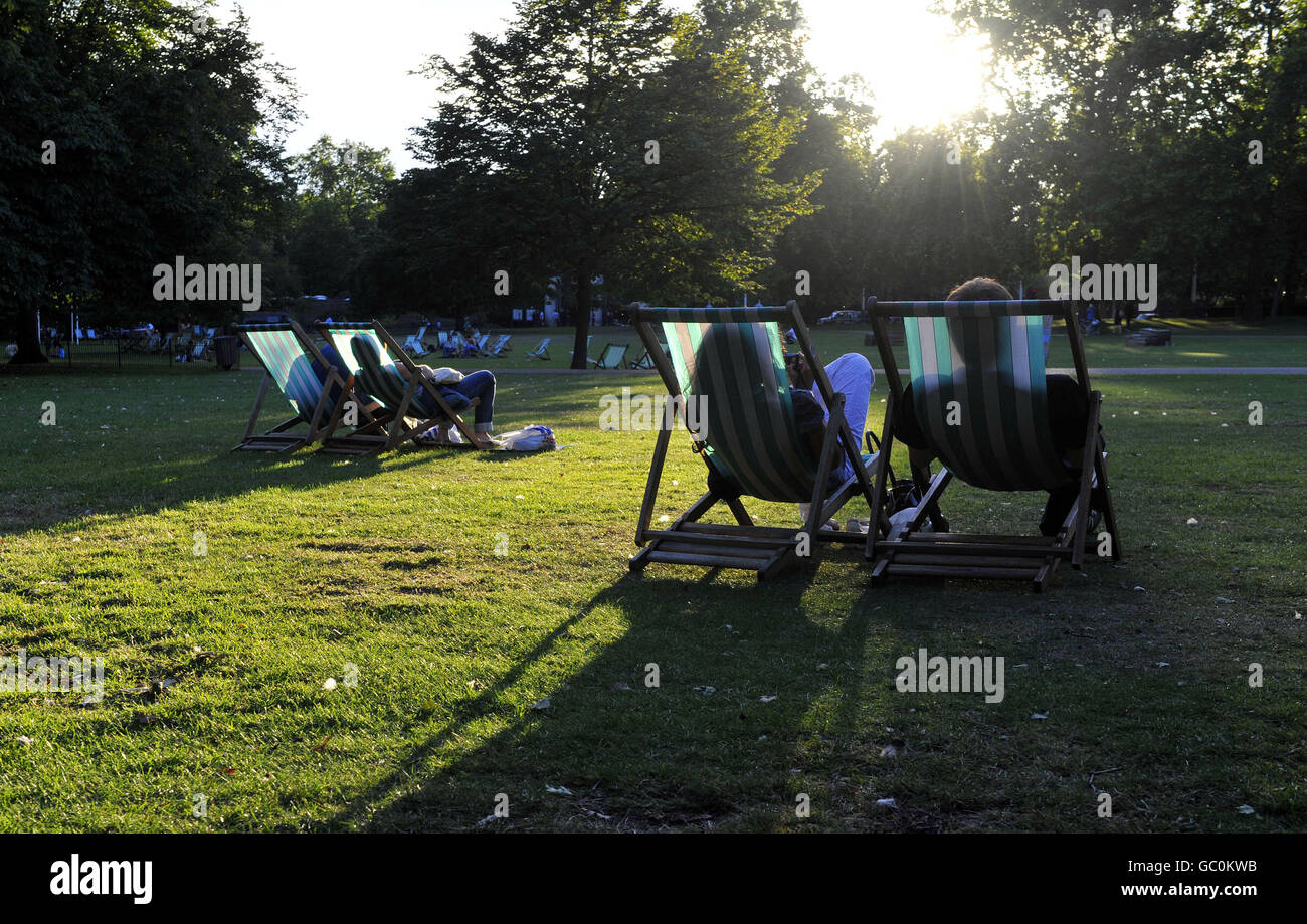 Les gens s'imprégnent des derniers moments du soleil du soir sur les transats du parc St James's de Londres. Banque D'Images