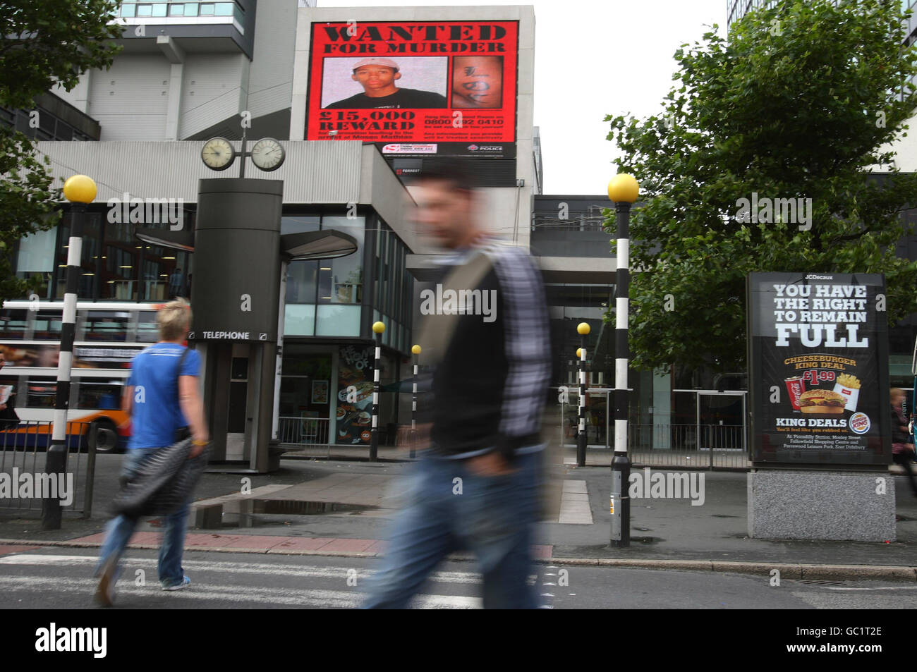 L'affiche "recherché" étant projeté sur un panneau d'affichage électronique dans les jardins de Piccadilly à Manchester montrant Moses Mathias, le garçon de 16 ans recherché dans le cadre du meurtre de Giuseppe Gregory qui a été abattu en mai. Banque D'Images