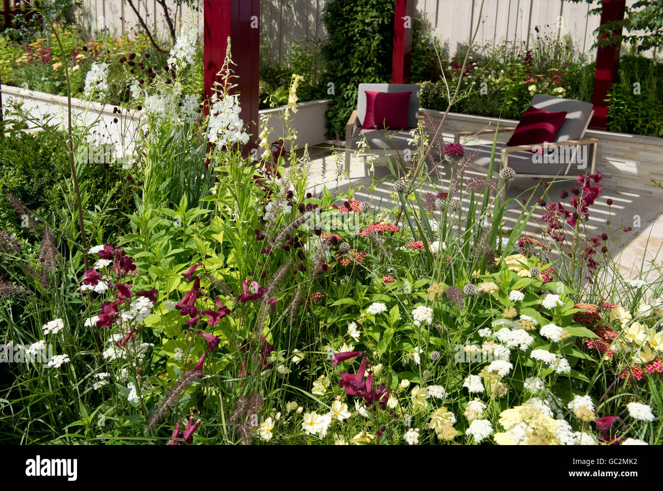 Un colurful pavillon rouge sur un coin salon en contrebas entouré de Frontières herbacées dans le Squire's 80e anniversaire Jardin. Banque D'Images