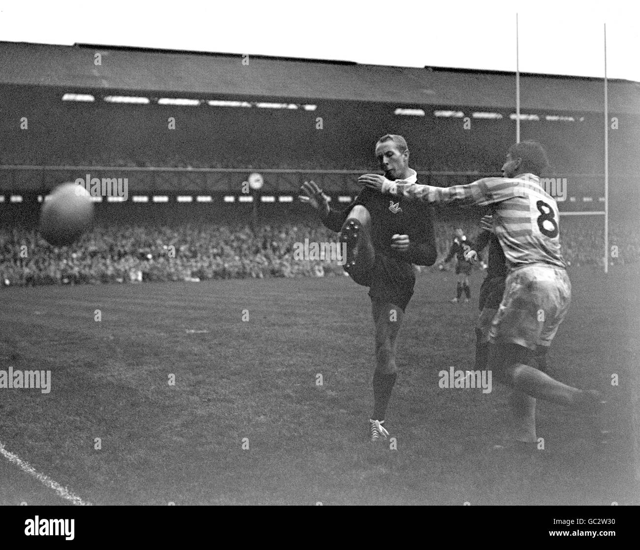 American Pete Dawkins (Oxford) fait sortir la balle de ses mains alors qu'il est attaqué par R. Leonard de Cambridge (8). Le boursier Rhodes joua auparavant au football américain et adaptait sa longue capacité de lancer à la ligne de rugby. Il est généralement considéré comme popularisant le lancer de bras à la ligne de sortie. Banque D'Images