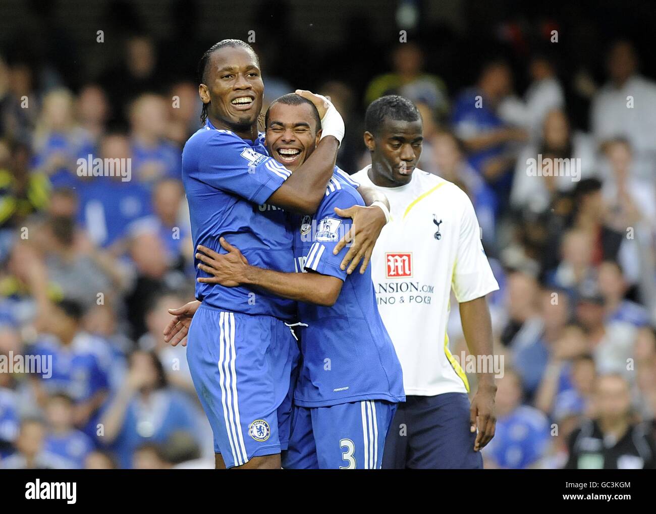 Didier Drogba (à gauche) de Chelsea célèbre le troisième but de ses côtés Avec son coéquipier Ashley Cole (au centre) comme Sébastien Bassong de Tottenham Hotspur (droite) se trouve en position de dejection Banque D'Images