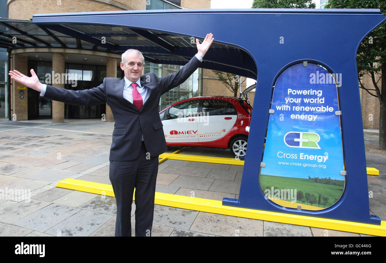 Joe Conway avec son chargeur de voiture solaire à Belfast.Le manque de soleil à Belfast n'a pas empêché le propriétaire du premier chargeur de voiture à énergie solaire d'Irlande du Nord de se brancher aujourd'hui. Banque D'Images