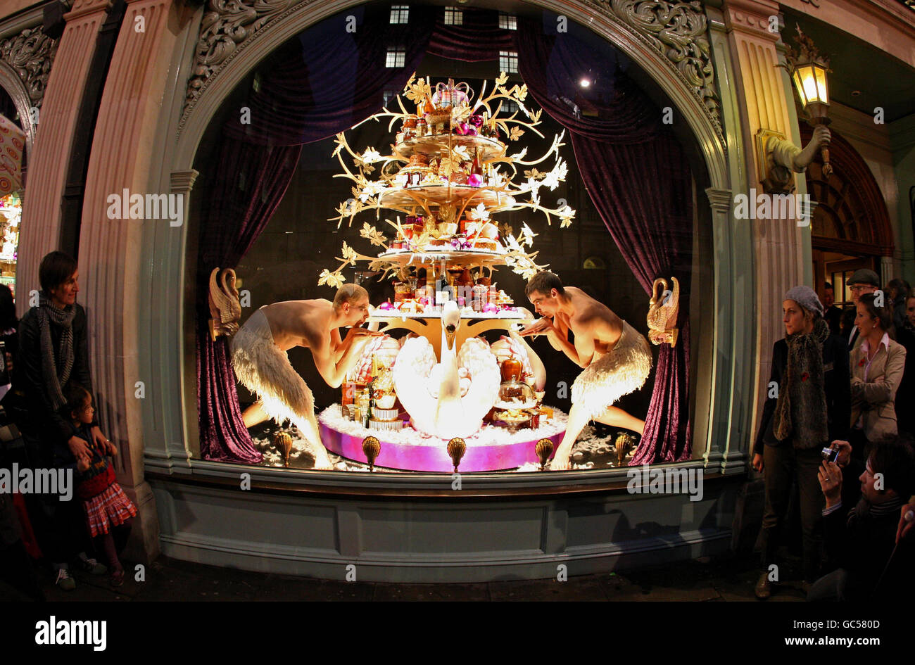 Les passants regardent des danseurs du « lac wan » de Matthew Bourne se produire dans la fenêtre de Fortnum & Masons à Piccadilly, Londres, lors du lancement de l'exposition de Noël du magasin. Banque D'Images