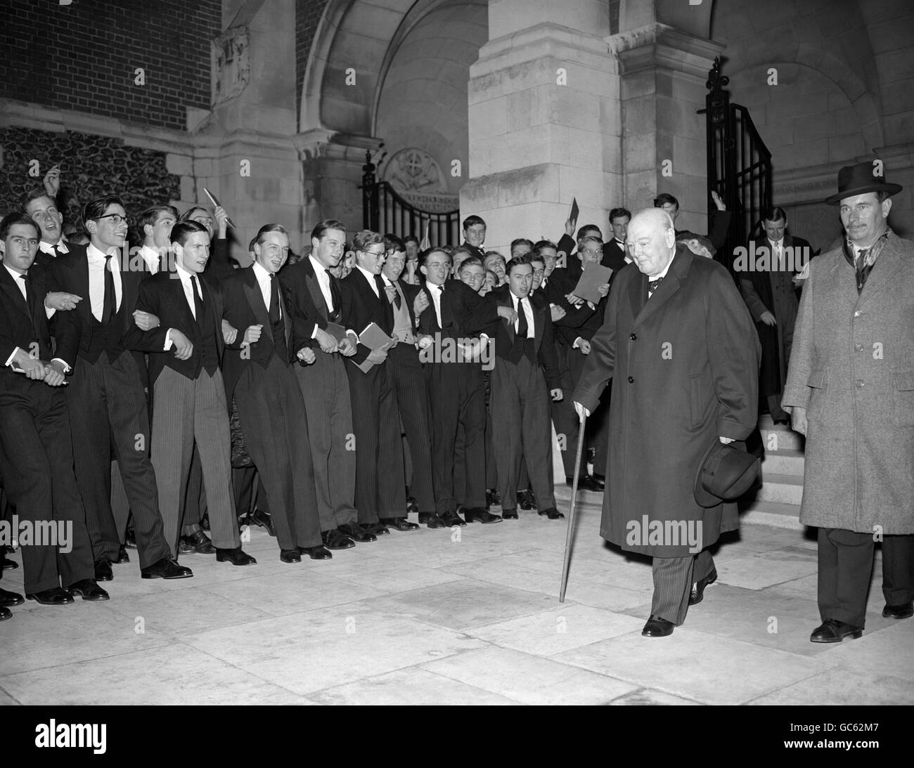 Sir Winston Churchill passe devant les rangs d'érudits enthousiastes lors d'une visite à sa vieille école, Harrow, pour le concert annuel de 'strongs'. Banque D'Images