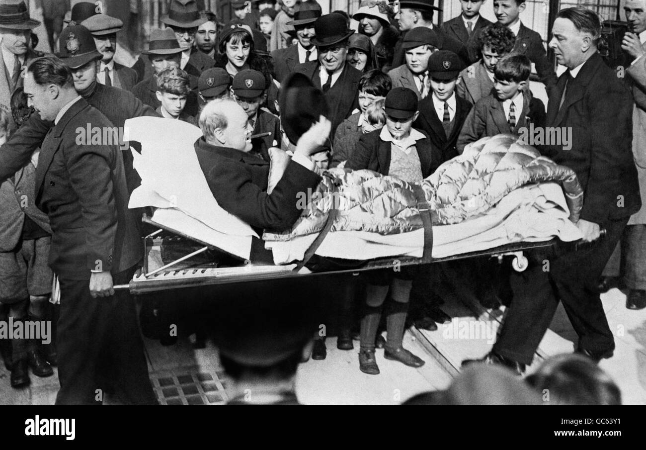 Winston Churchill (avec un cigare et un chapeau) étant pris par civière  dans son appartement de Londres après avoir quitté une maison de retraite  du West End où il souffrait de paratyphoïde