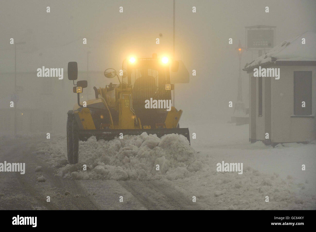 Un excaveur JCB élimine la neige à Princetown, Dartmoor, Devon, où la neige est tombée la nuit et s'est bloquée au large de la ville. Banque D'Images