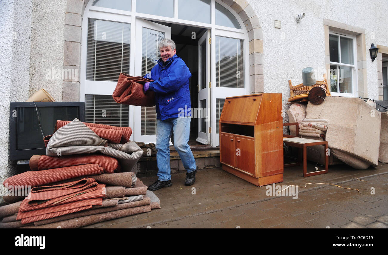 Peter Ingles aide à nettoyer la maison de son beau-père à Cockermouth après le recul des eaux d'inondation. Banque D'Images