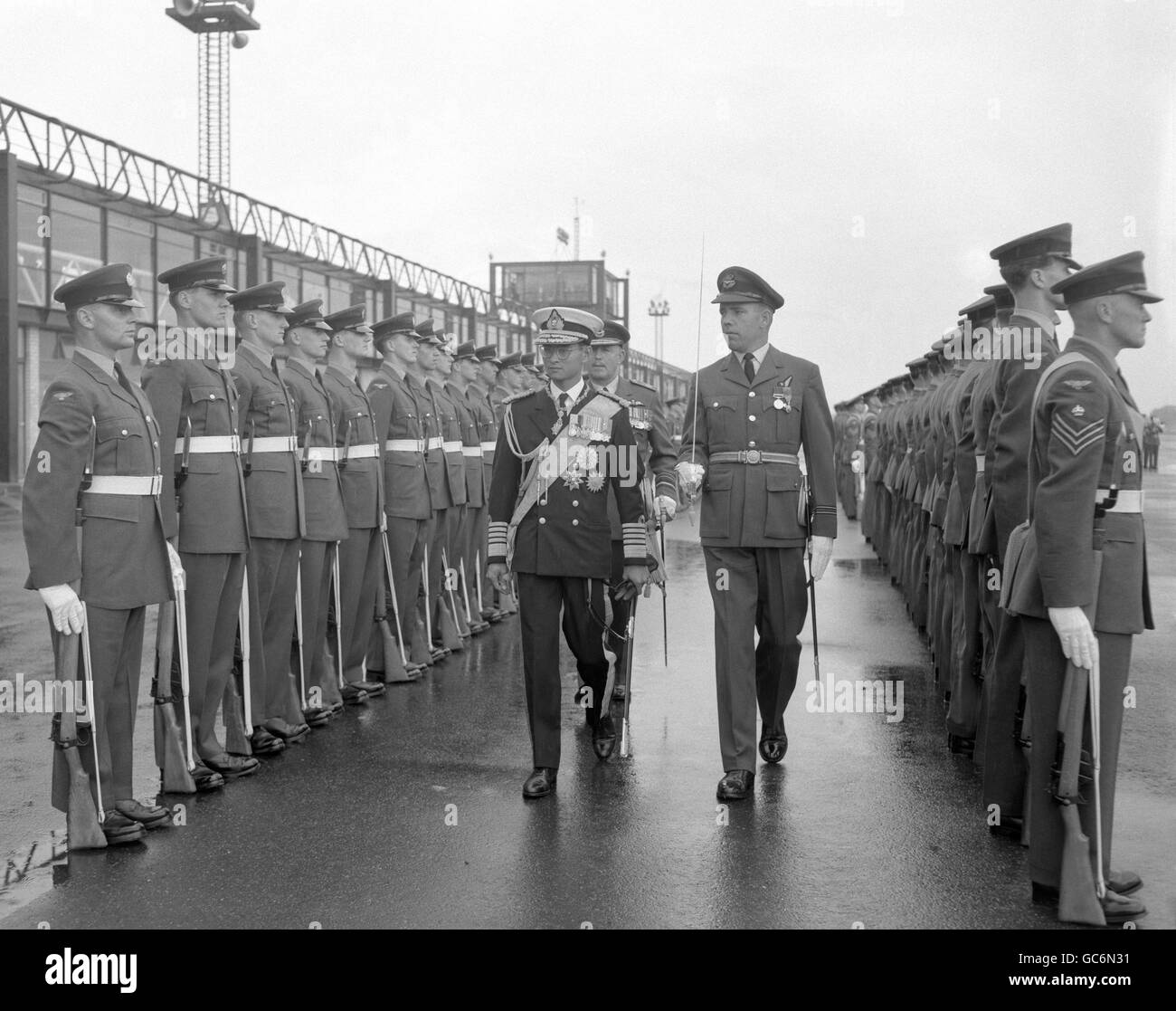 Le roi Bhumibol Aduladej de Thaïlande, en uniforme naval, inspecte un garde d'honneur de la Royal Air Force à l'aéroport de Gatwick à son arrivée pour une visite d'État à Londres. Banque D'Images