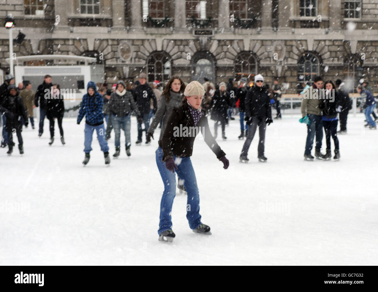 Les patineurs apprécient le temps d'hiver à la patinoire Somerset House tandis que la neige tombe au-dessus de Londres. Banque D'Images