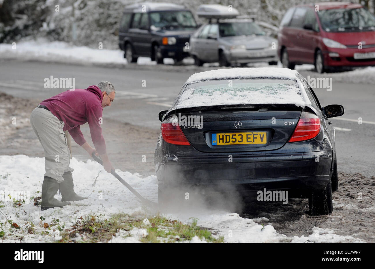 Un homme utilise une pelle alors qu'il tente de déplacer sa voiture du côté de la route après une nuit de neige à Basingstoke, Hampshire. Banque D'Images
