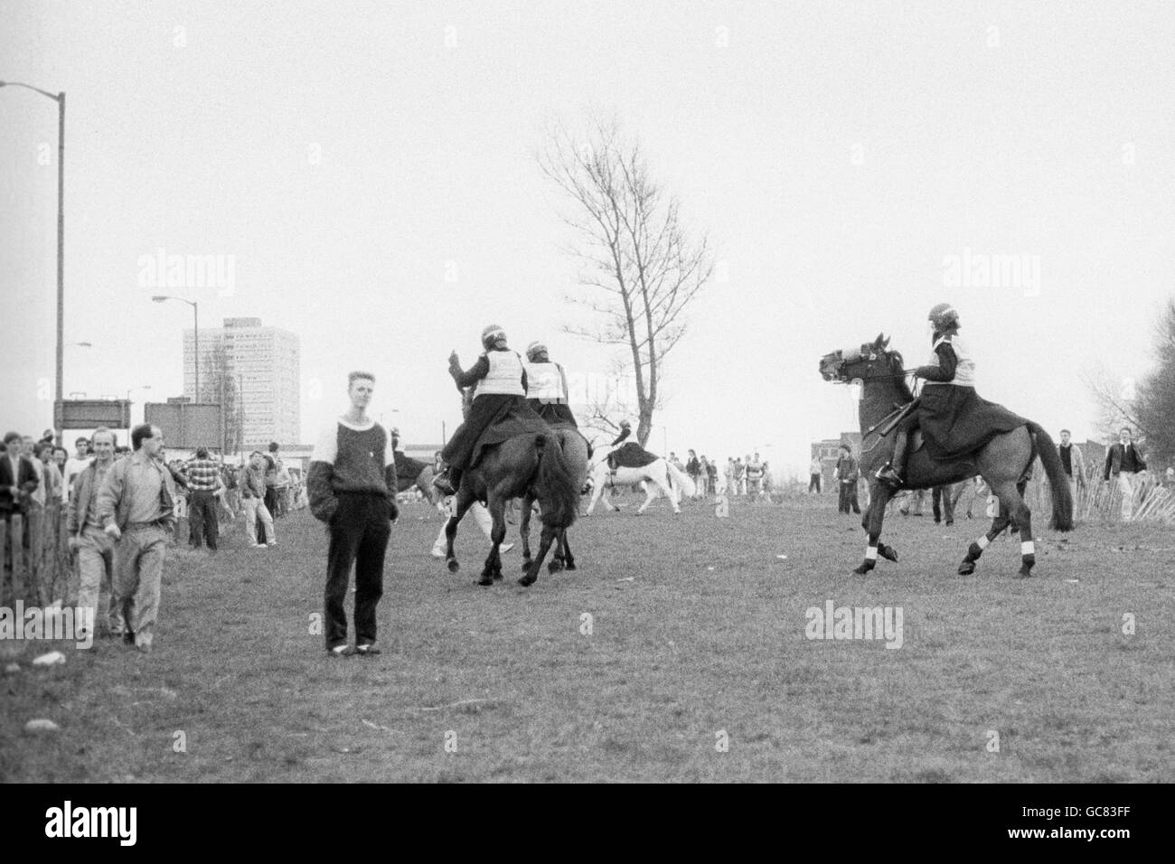 La police anti-émeute à cheval essaie de contrôler la foule en se retrouvant au sol. Des problèmes se sont déclarés entre les fans rivaux sur les terres en friche près du sol. Banque D'Images