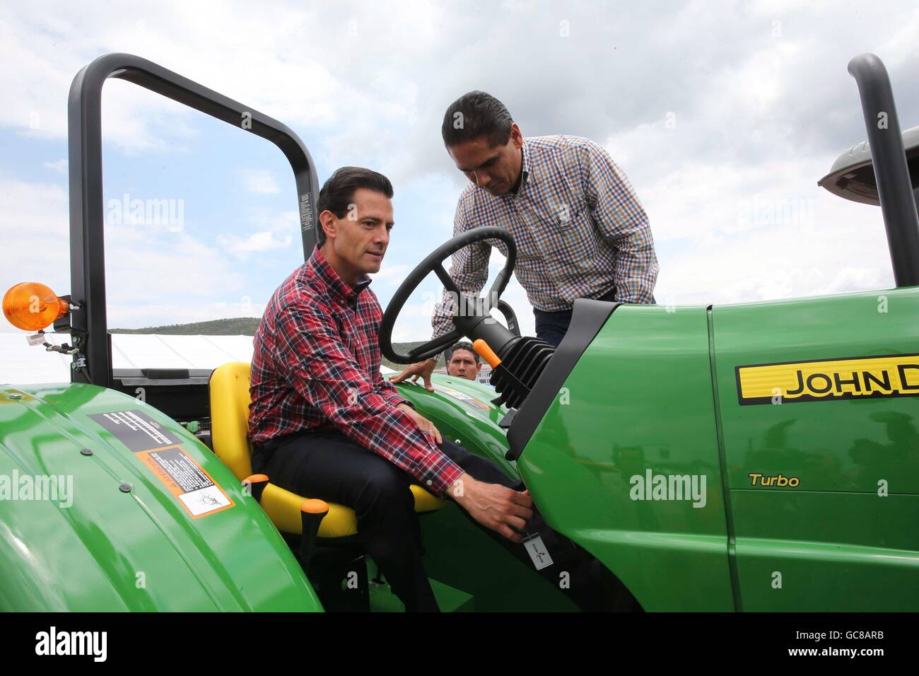 Le Président mexicain Enrique Pena Nieto, assis, est comment faire fonctionner un tracteur John Deere par Michoacan Gouverneur Silvano auréoles lors d'une cérémonie à livrer 600 tracteurs agricoles aux paysans pauvres, le 5 juillet 2016 dans La Goleta, Charo, Michoacan, Mexique. Le programme gouvernemental prévoit de fournir 25 000 tracteurs aux agriculteurs pauvres d'ici 2018 dans l'espoir d'améliorer la production agricole dans tout le pays. Banque D'Images