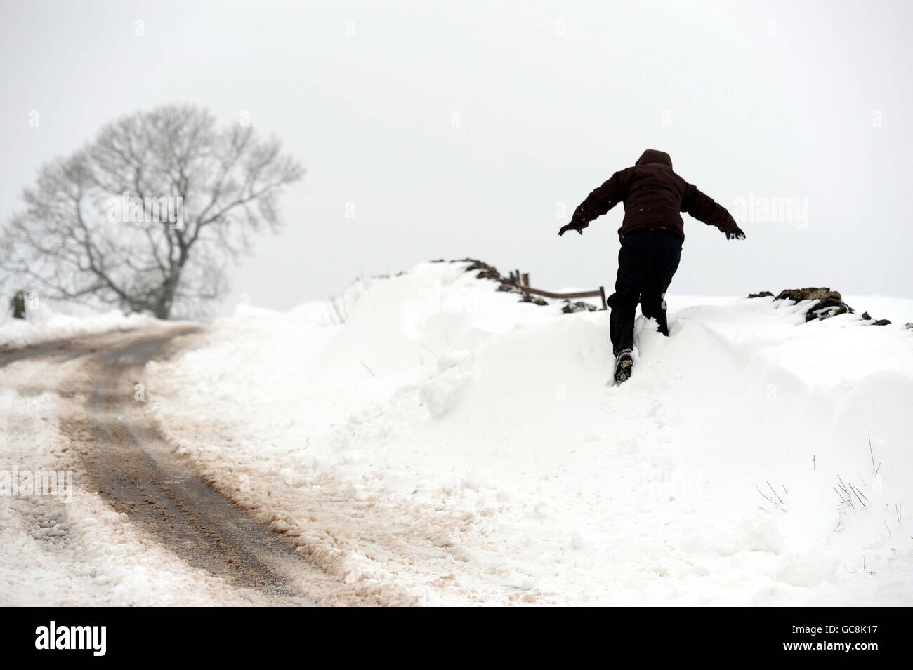 Un piéton marche le long d'une route à Buxton, dans le Derbyshire, où des dérives de neige jusqu'à quatre pieds de profondeur ont été signalées. Banque D'Images