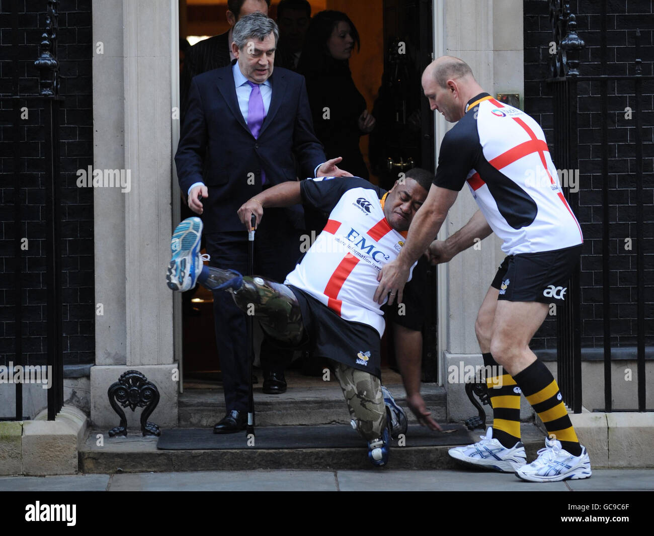Le premier ministre Gordon Brown et le joueur de rugby Lawrence Dallaglio(à droite) aident Derek Derenalagi (au centre) à se trouver à la porte du 10 Downing Street, Londres. L'ancien soldat qui a perdu les deux jambes en Afghanistan en 2007 était là pour promouvoir un match de rugby du Saint-Georges Day afin de recueillir de l'argent pour aider les héros. Banque D'Images