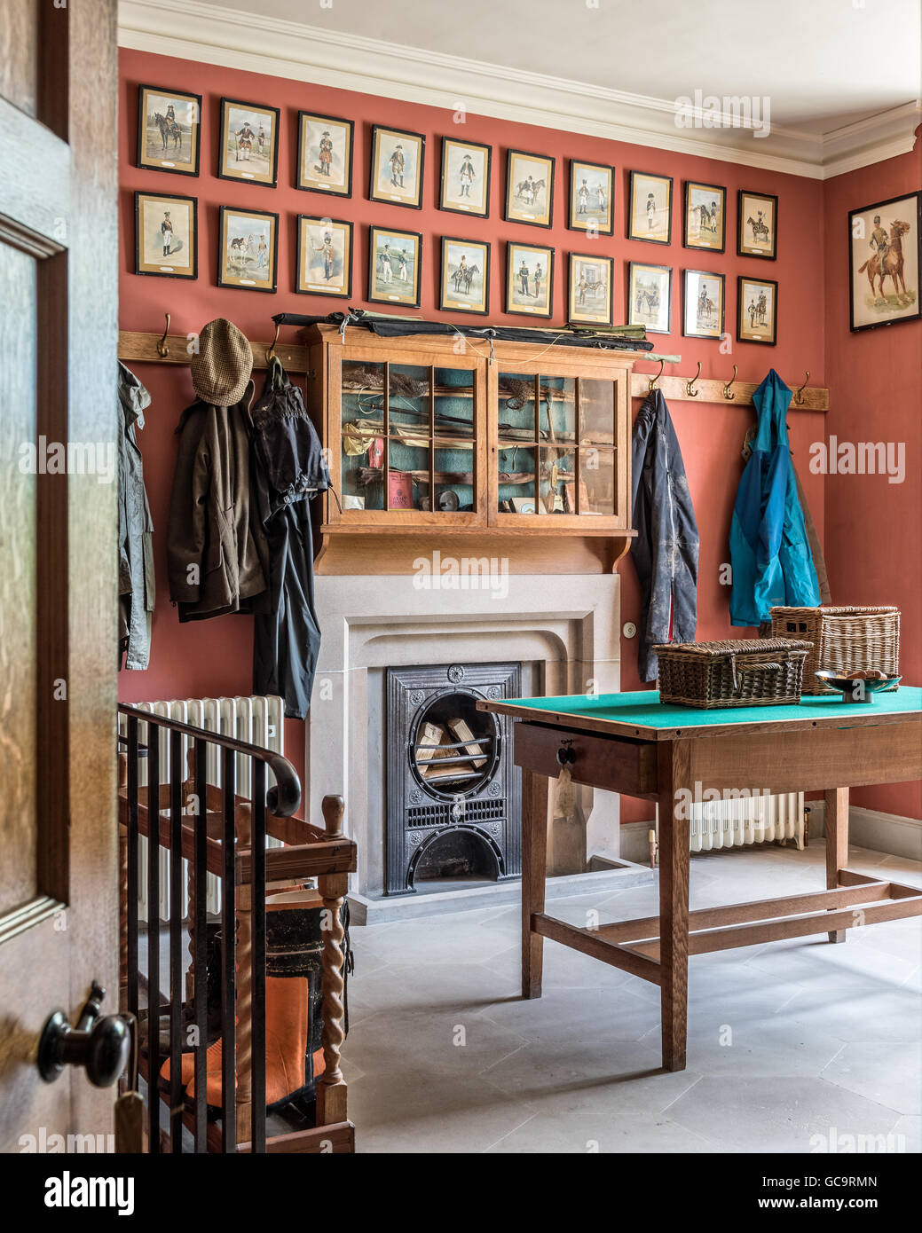 L'uniforme militaire encadrée ligne imprime le mur au-dessus d'un ancien placard des armes à feu dans une ancienne salle d'armes à feu avec des patères et cheminée Banque D'Images
