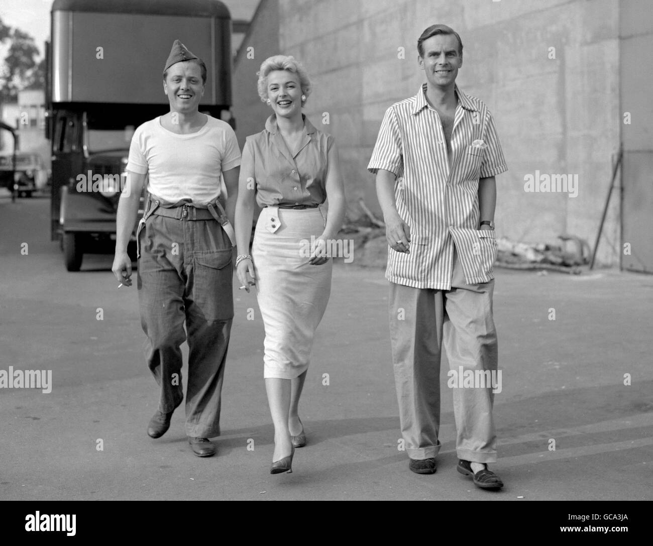 Il est temps de se promener et de fumer avant qu'ils n'aient à se présenter à nouveau en parade. Richard Attenborough (à gauche), Jill Adams et Ian Carmichael se relaxaient entre deux prises sur le nouveau film humoristique des frères Boutting de la vie de l'Armée de terre 'Private's Progress' Banque D'Images