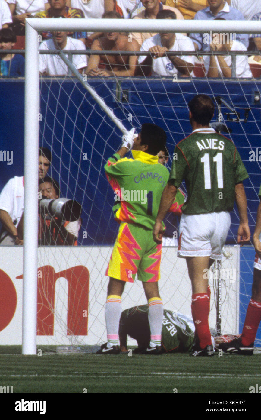 Le Marcelino Bernal (au sol) du Mexique tente de se démêler du filet de but après être tombé dans le but. Le gardien de but du Mexique Jorge Campos tire sur le poteau de guidage brisé. Banque D'Images