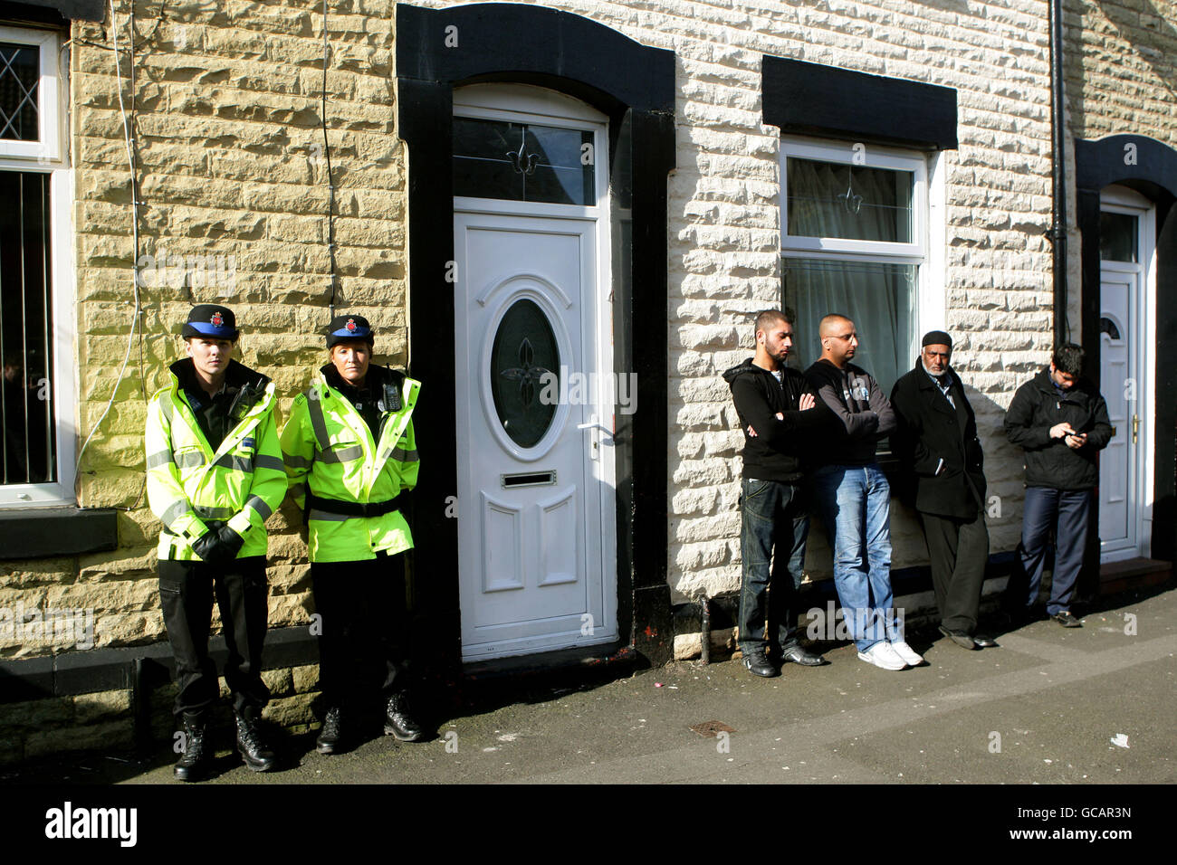 La police et les amis se trouvent à l'extérieur de la maison d'Akila Naqqash à Oldham, dans le Grand Manchester, mère du garçon de cinq ans Sahil, qui a été enlevé au Pakistan avec son père. Banque D'Images