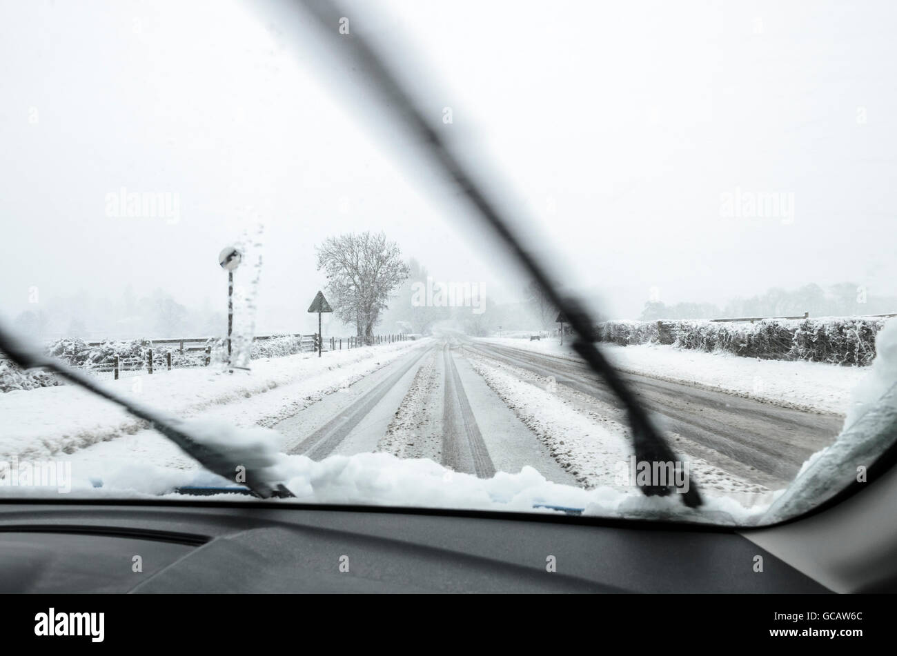 La vue si le pare-brise d'une automobile étant couvert de neige le long d'une route rurale. Banque D'Images La vue si le pare-brise d'une automobile étant couvert de neige le long d'une route rurale. Banque D'Images
