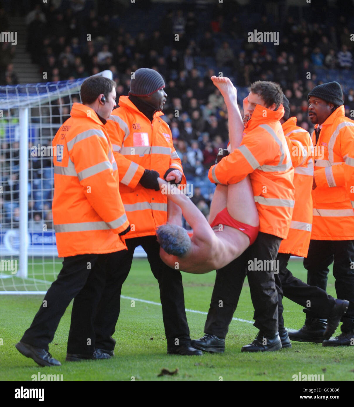 Un Streaker est escorté hors du terrain par des stewards pendant le match de championnat de Coca-Cola à Loftus Road, Londres. Banque D'Images