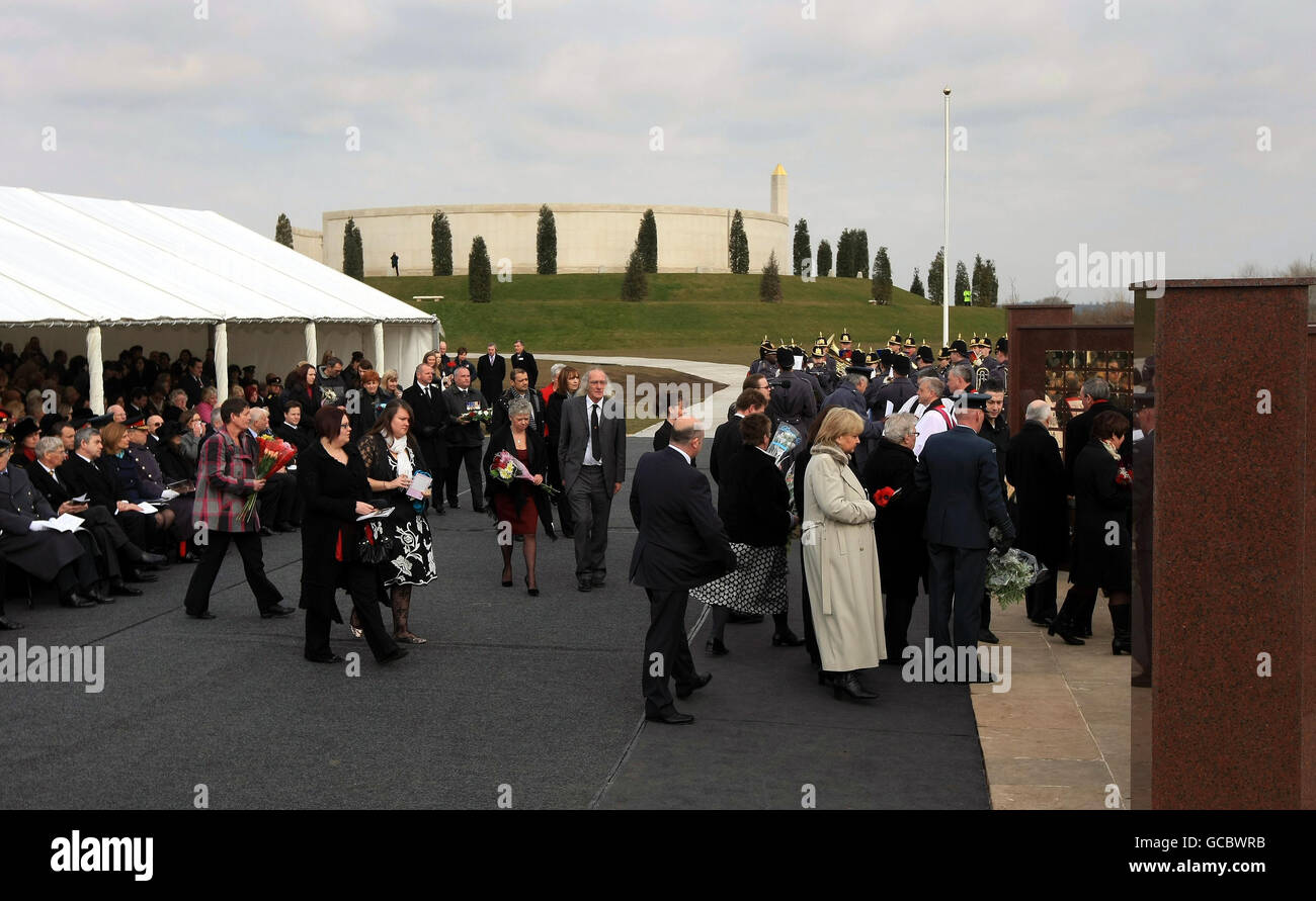 Les membres de la famille du personnel de service déchu s'approchent du mur du mémorial de Basra à l'arboretum du mémorial national près d'Alrewas dans le Staffordshire, pour déposer des fleurs pendant un service afin de consacrer à nouveau le mur après son déplacement de Bassorah, en Irak. Banque D'Images