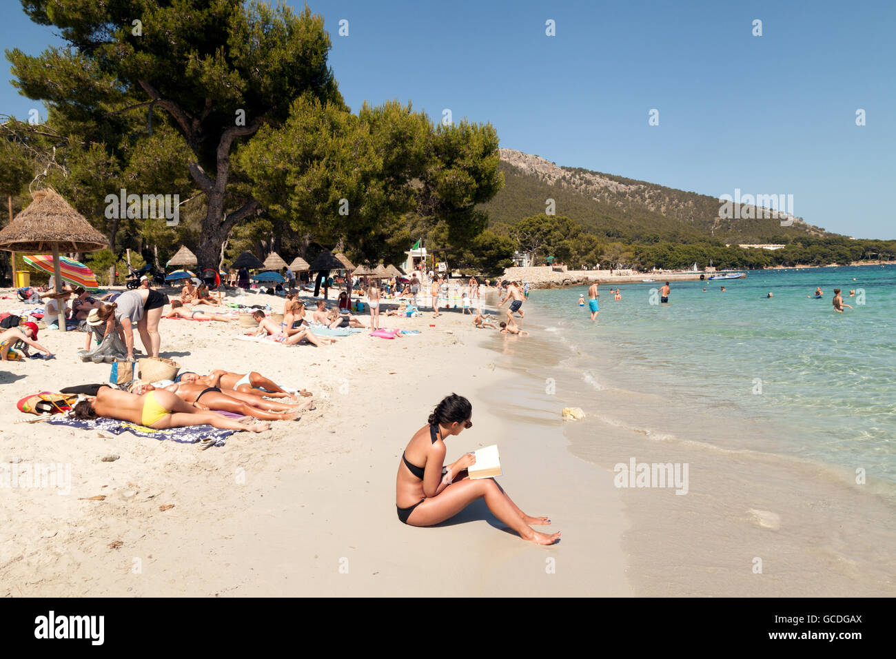 Seule femme lisant un livre sur une plage de vacances, Cala Formentor, Majorque Îles Baléares l'Europe Banque D'Images