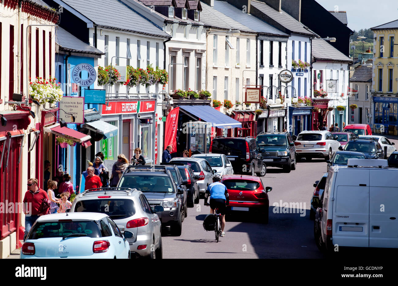 Les piétons, les voitures et les cyclistes le long d'une rue animée ; Schull, comté de Cork, Irlande Banque D'Images