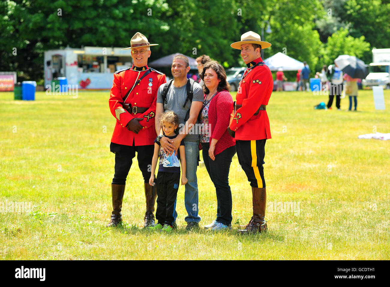 Une famille de poser pour des photos avec deux gendarmes à un festival de la fête du Canada à London, en Ontario. Banque D'Images