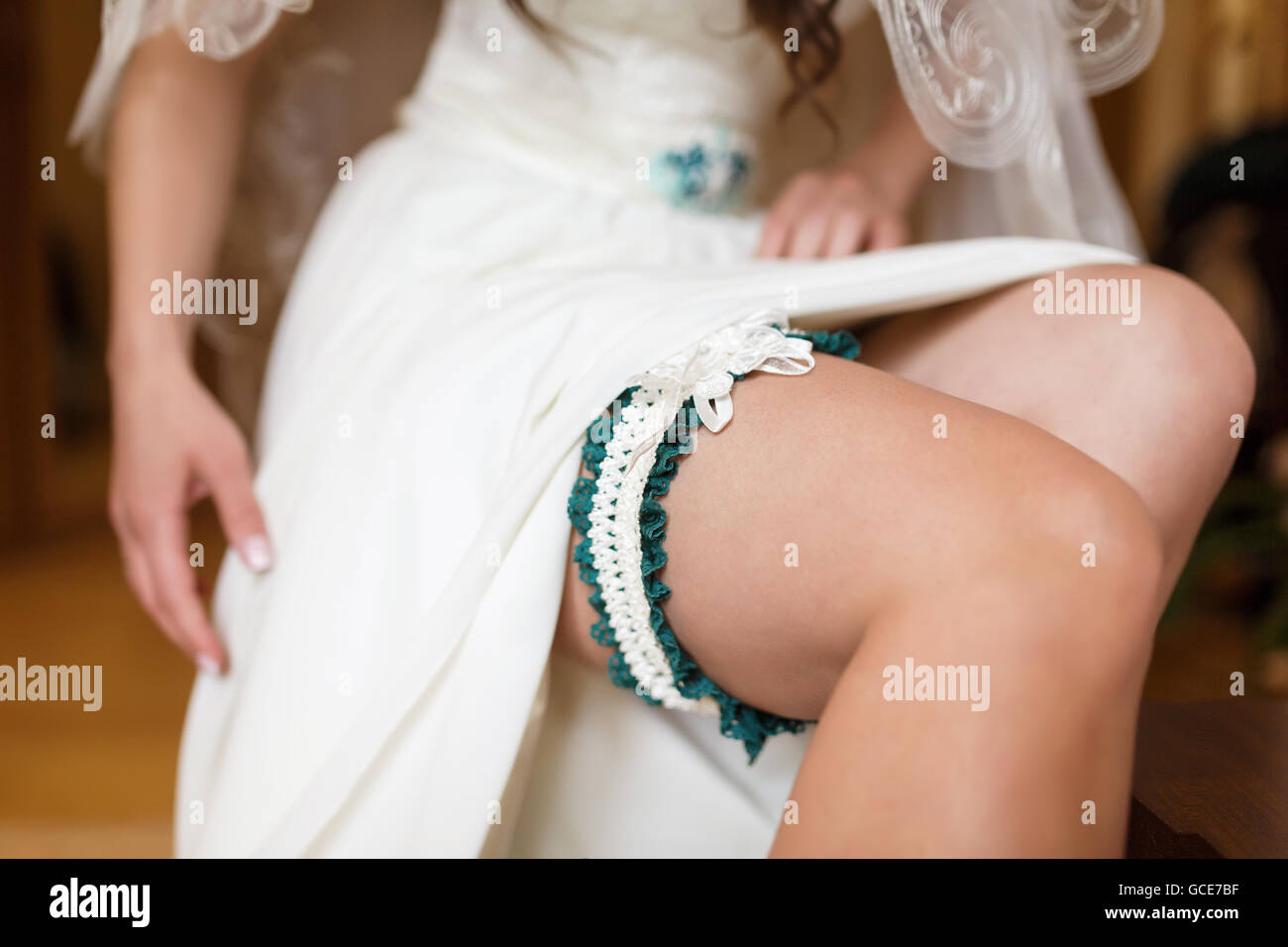 Jolie mariée met sur le porte-jarretelles sur sa jambe dans la chambre Banque D'Images