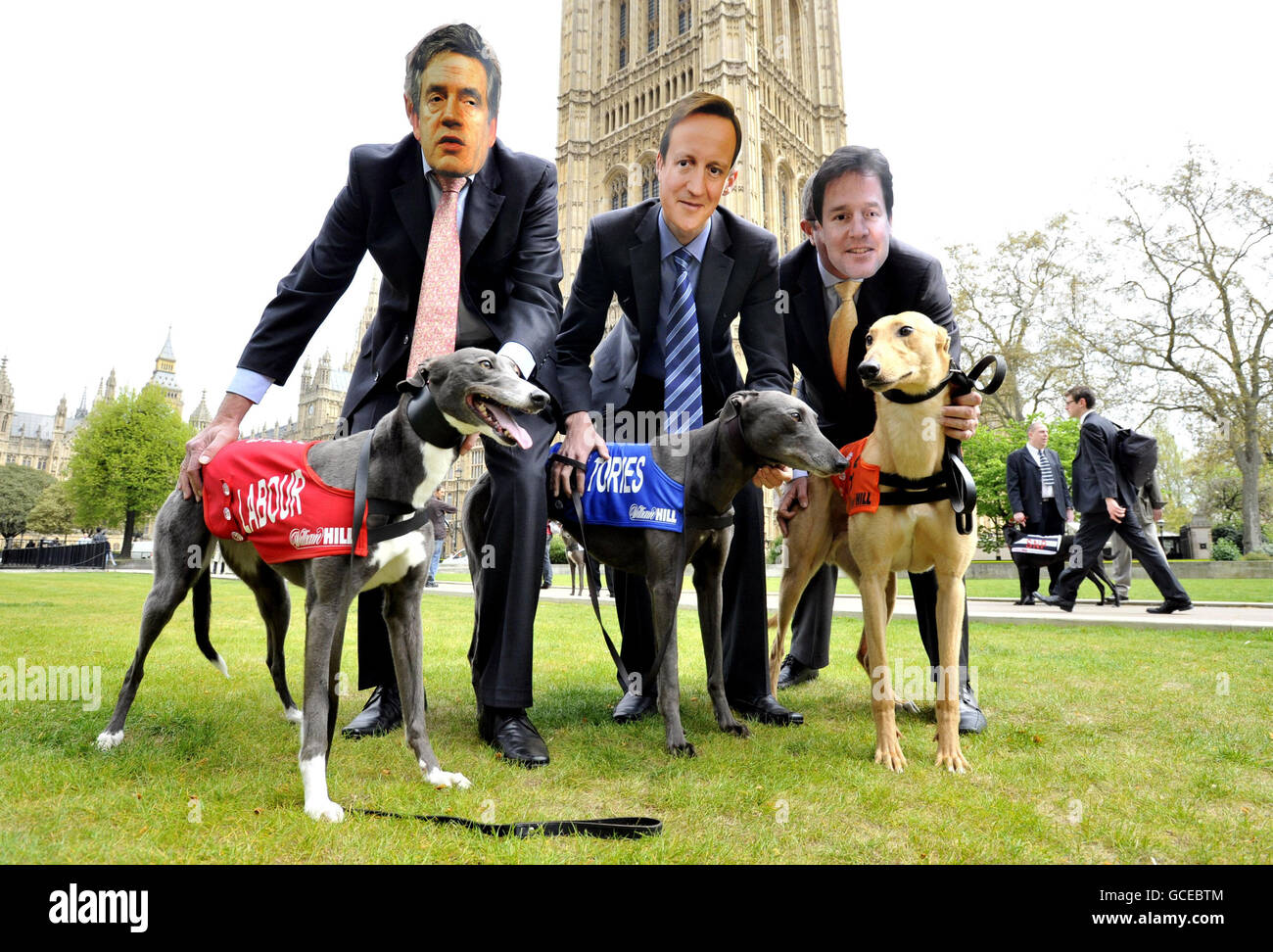 Des gens portant des masques de Gordon Brown, David Cameron et Nick Clegg sur Abingdon Green, Londres, pour prévisualiser une course impliquant six lévriers qui représenteront chacune des six principales parties lors d'une course au stade de Wimbledon le vendredi 30 avril. Banque D'Images