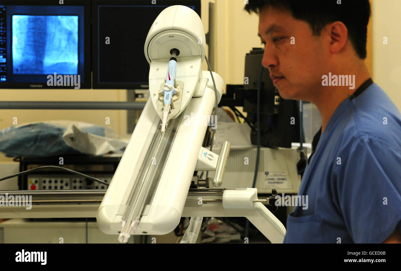 Chirurgien Dr Andre ng, cardiologue consultant à l'hôpital de Glenfield et maître de conférences en sciences cardiovasculaires à l'université de Leicester, avec un bras robot à l'hôpital de Glenfield à Leicester, avant la première opération cardiaque à distance réalisée avec le bras sur patient Kenneth Crocker, 70, De Burton on Trent. Banque D'Images