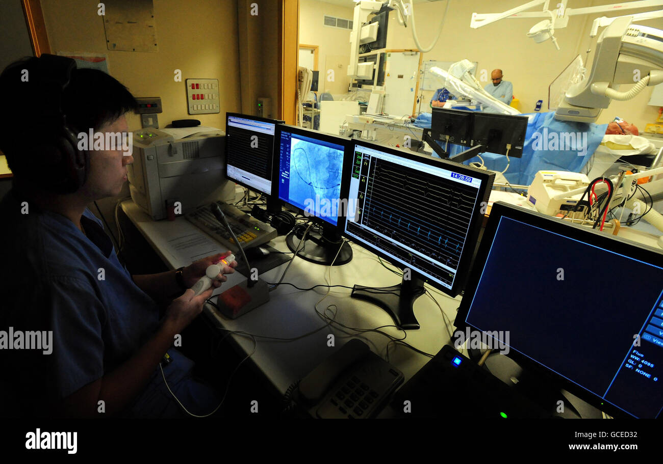 Le chirurgien Dr Andre ng, cardiologue consultant à l'hôpital de Glenfield et maître de conférences en sciences cardiovasculaires à l'université de Leicester, regarde un écran pendant qu'il guide un cathéter à l'aide d'un bras robot à l'hôpital de Glenfield à Leicester, Au cours de la première opération cardiaque à distance au monde réalisée avec le bras sur le patient Kenneth Crocker, 70, de Burton on Trent. Banque D'Images