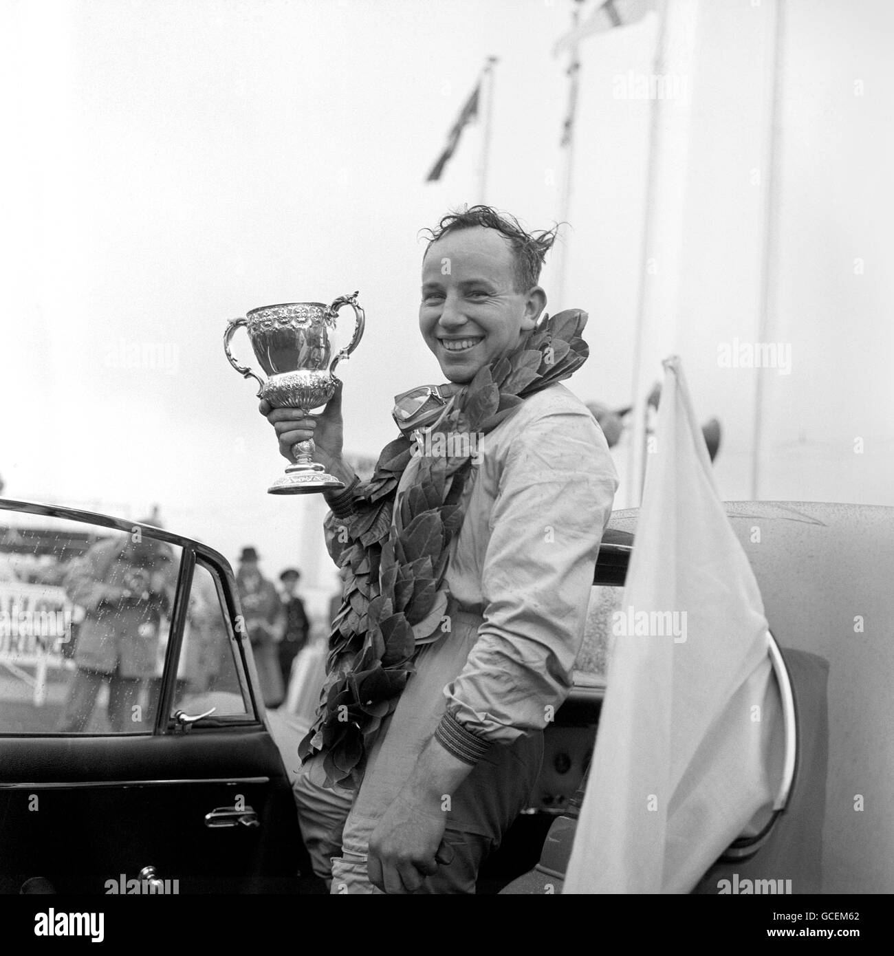 John Surtees, l'actuel champion du monde du motocyclisme, portant les lauriers de son vainqueur, détient le Trophée Glover après avoir remporté sa première course automobile majeure, le Trophée Glover '100', dans un Cooper Climax. Banque D'Images