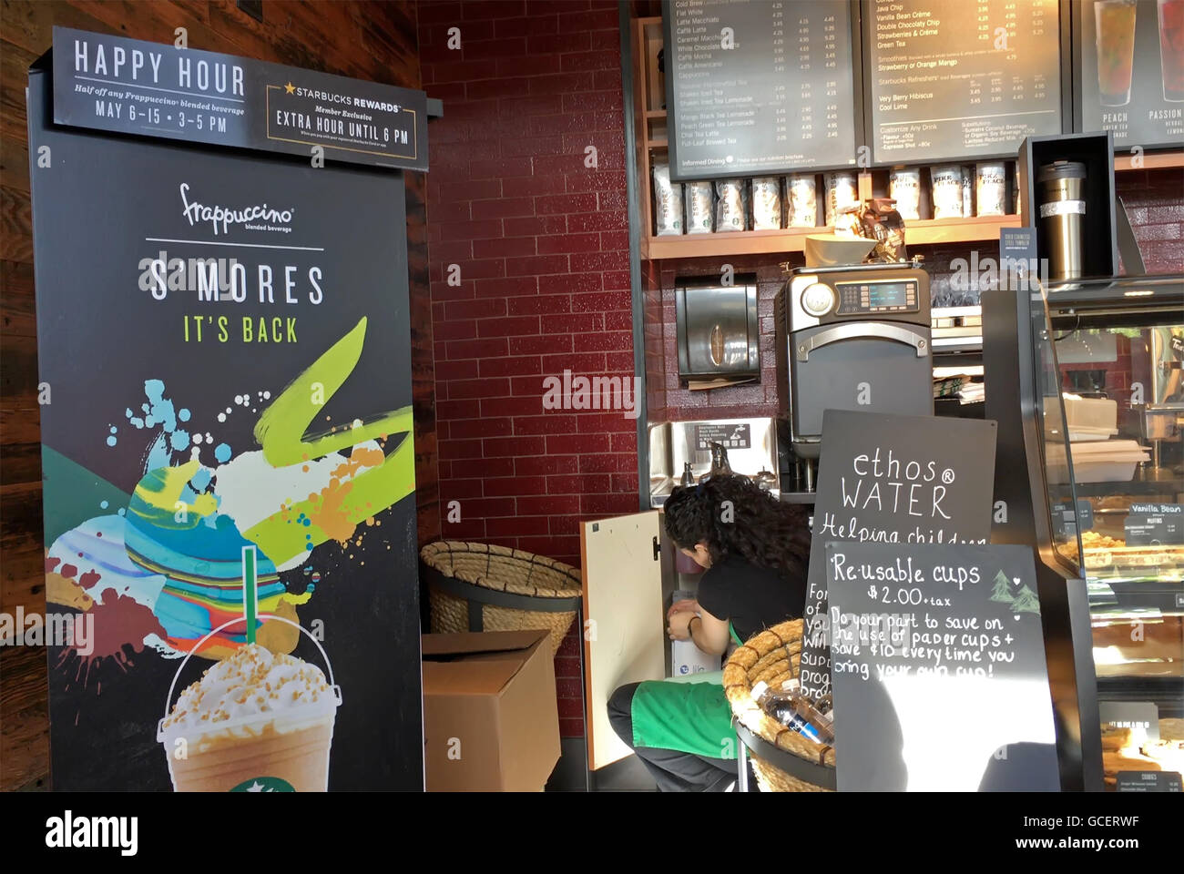 L'empoissonnement travailleur tasses avec l'heure de l'affichage à l'intérieur de signer la vente du café Starbucks Banque D'Images