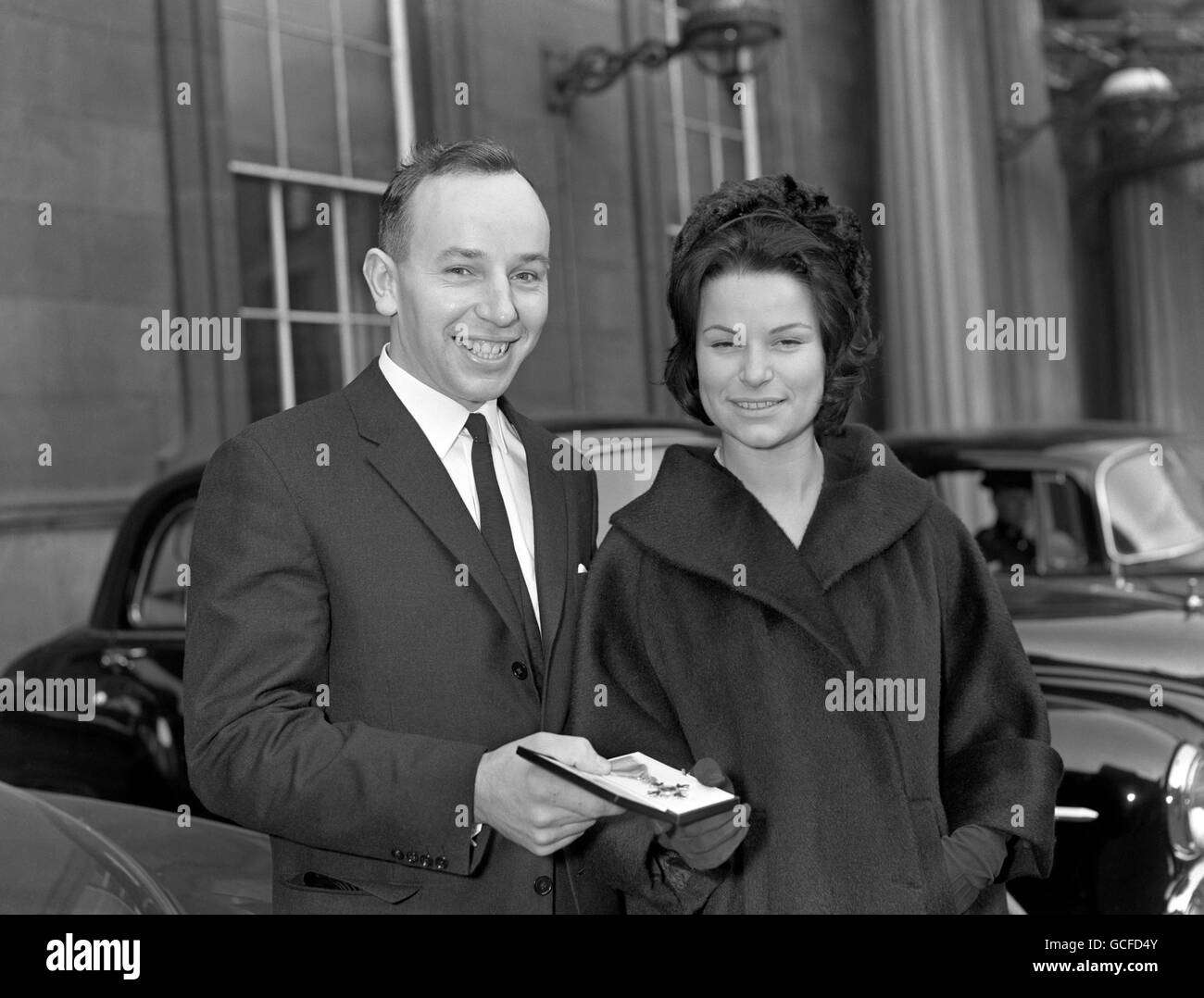 John Surtees, ancien motocycliste et maintenant pilote de voiture, avec sa fiancée Patricia Burke, après avoir reçu un OBE. Banque D'Images