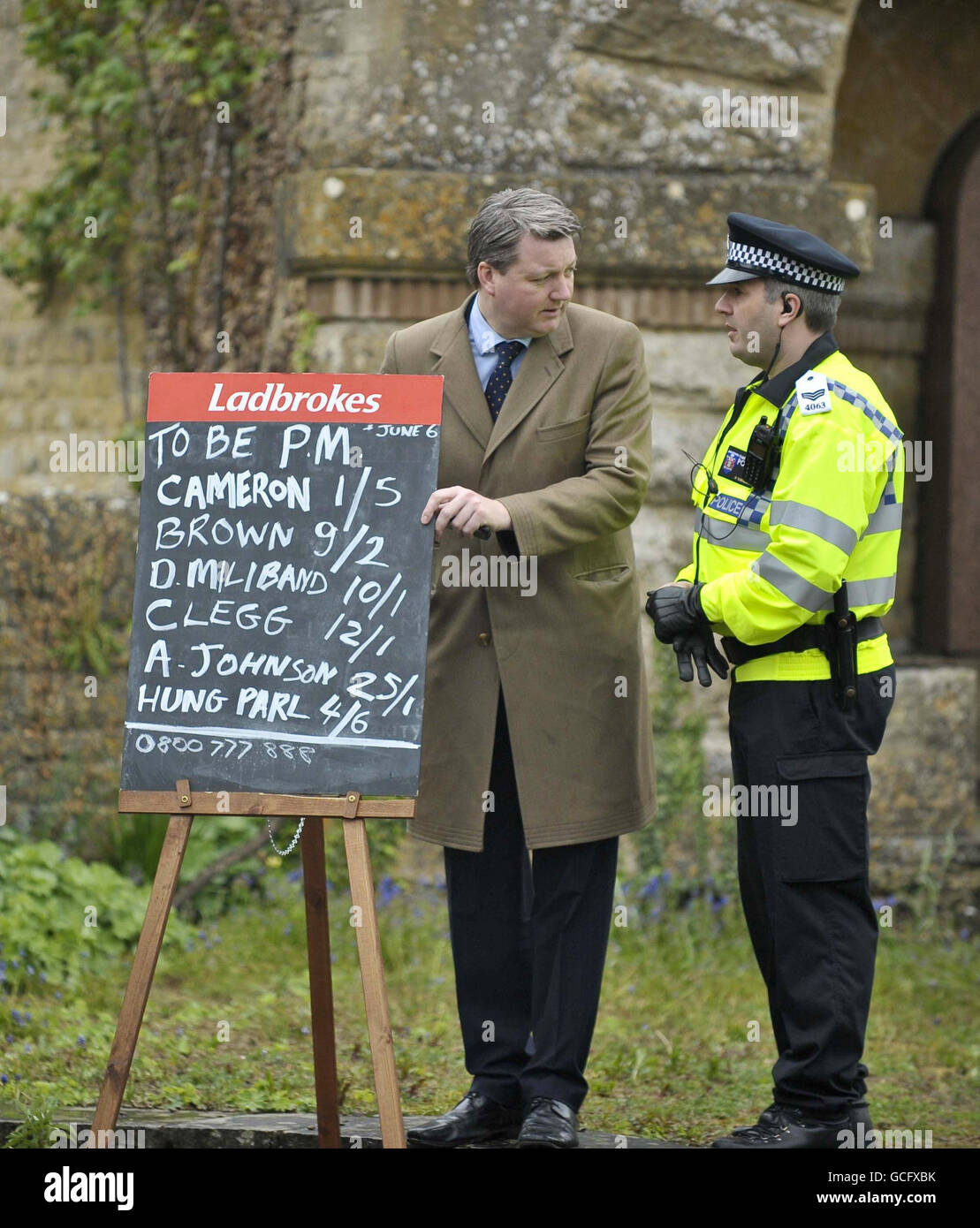 Un policier discute avec un bookmaker à l'extérieur du Spelsbury Memorial Hall, dans la circonscription de Witney de David Cameron, dans le Oxfordshire, après que M. Cameron et sa femme Samantha aient exprimé leurs votes. Banque D'Images