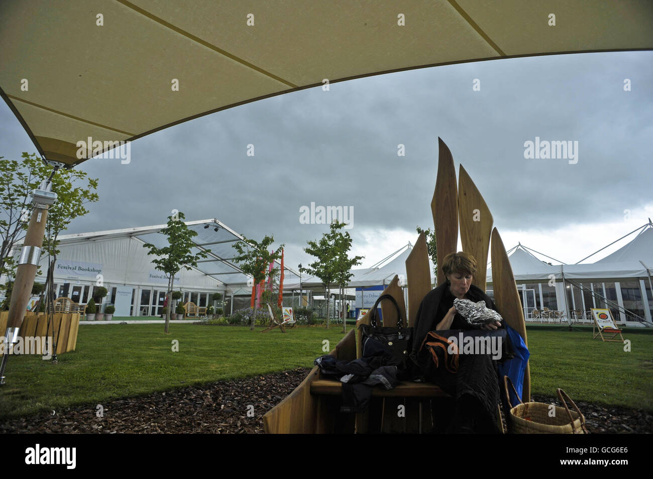 Une femme s'assoit et mange sous une toile tandis que le ciel sombre de couvaison survole le Hay Festival à Hay-on-Wye. Banque D'Images